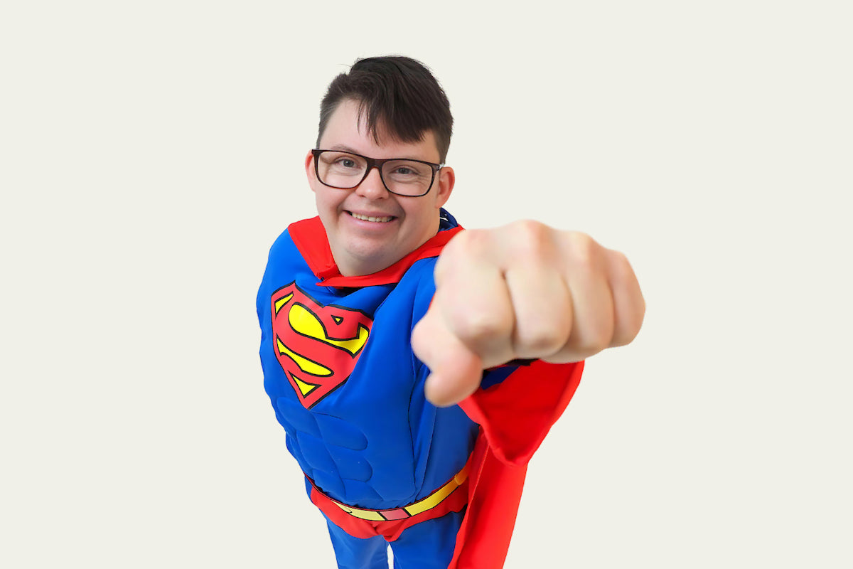 Jaunas vyras su Supermeno herojaus kostiumu, pozuojantis fotosesijai.